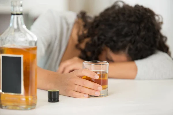 女性を背景にしたアルコールのボトルとガラス — ストック写真