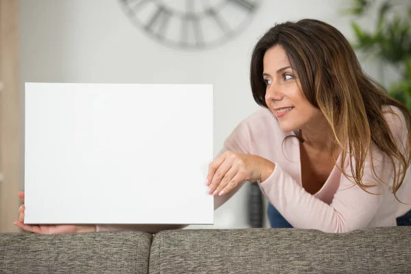 Frau Hält Leeres Schild Auf Der Rückseite Eines Sofas — Stockfoto