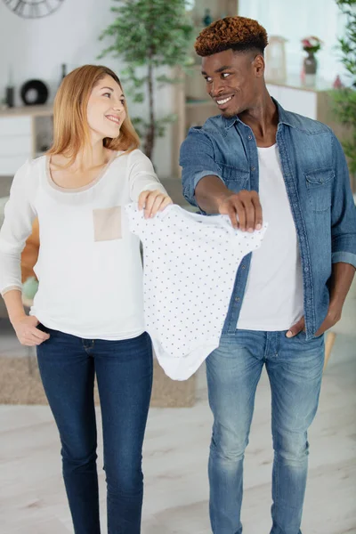 抱着婴儿用品笑着的怀孕夫妇 — 图库照片