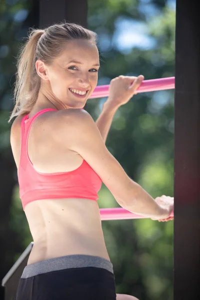 健康な運動選手の女性は屋外の水平バーで運動をします — ストック写真