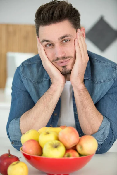 一个男人的画像坐在一碗苹果旁边 — 图库照片