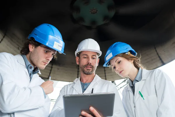 Werknemers Kijken Naar Een Tablet Onder Een Turbine — Stockfoto