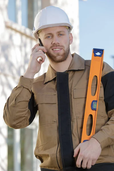 Constructor Manteniendo Nivel Espíritu Hablando Por Teléfono — Foto de Stock