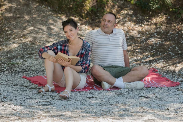 幸せなカップルはピクニックで本と一緒に横たわっていた — ストック写真
