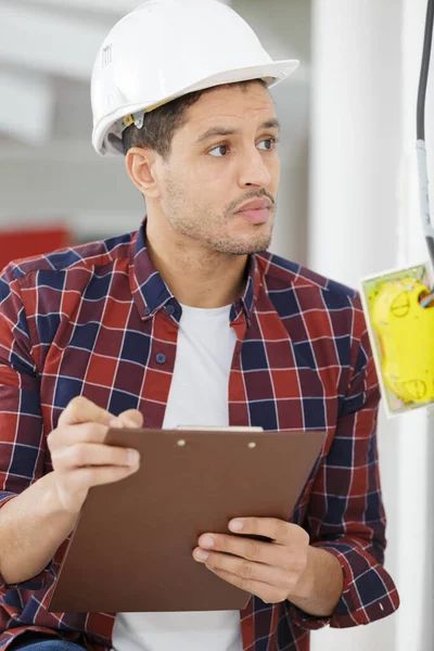 Bell Elettricista Sorridente Che Tiene Appunti Vicino Alla Scatola Elettrica — Foto Stock