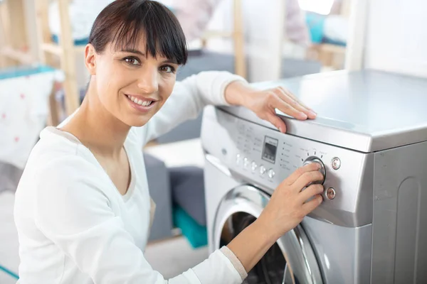 微笑的女人在洗衣机上设定拨号盘 — 图库照片