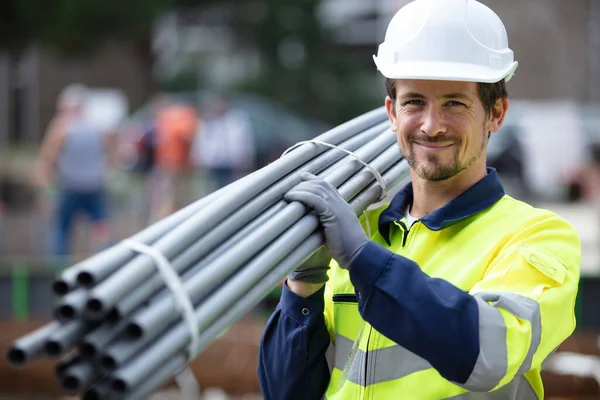 Arbeiter Trägt Bündel Mit Pfeifen Auf Der Schulter — Stockfoto