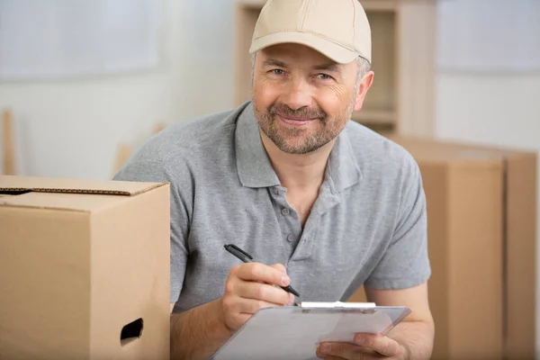 delivery man with cardboard box checking address list