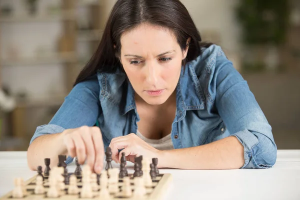 woman at home playing chess alone