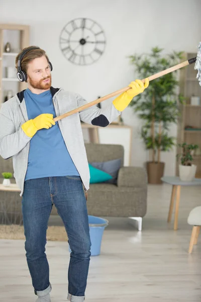 Young Man Cleaning Home Listening Music — Stockfoto