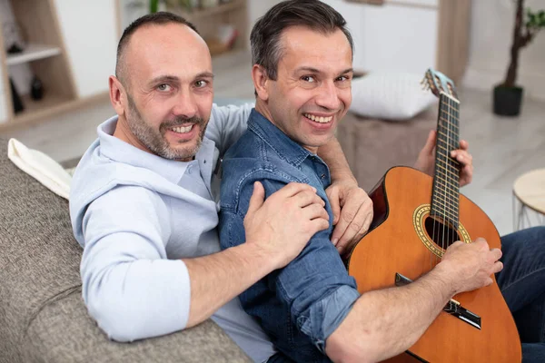 Pareja Gay Con Guitarra Sentado Sofá Casa —  Fotos de Stock