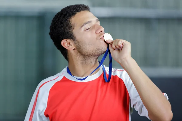 man in running gear kissing medal