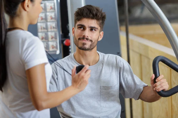 Entrenador Personal Que Muestra Tiempo Hombre Utilizando Máquina Gimnasio — Foto de Stock