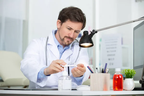 Doktor Vid Sitt Skrivbord Desinficerar Händerna — Stockfoto