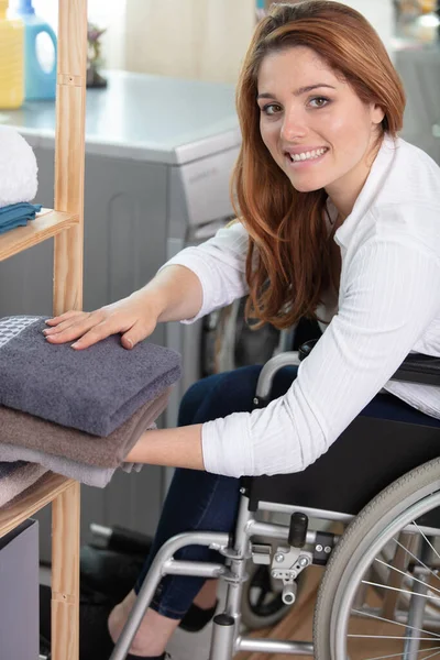 young disabled woman on wheelchair tidying up clean laundry