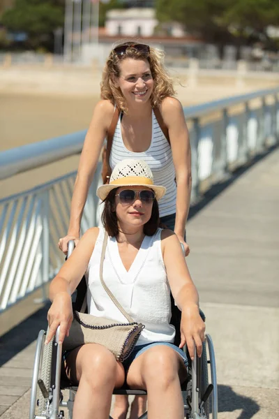 Lady Pushes Female Friend Wheelchair While Summer Holiday — Stockfoto