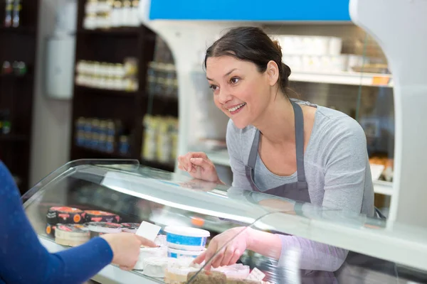 sales clerk serving at cheese counter