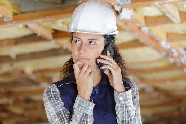 worried female construction worker using phone at a construction site