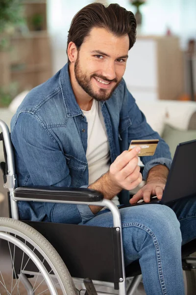 Χαμογελαστός Άνδρας Αναπηρική Καρέκλα Κρατώντας Πιστωτική Κάρτα Και Χρησιμοποιώντας Φορητό — Φωτογραφία Αρχείου