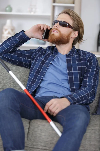 blind man on the phone sitting on sofa at home