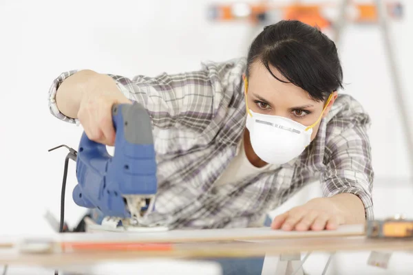 woman cutting furniture in workshop