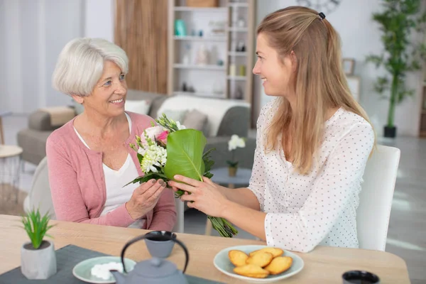 Vacker Vuxen Kvinna Ger Blommor Till Sin Mogna Mor — Stockfoto