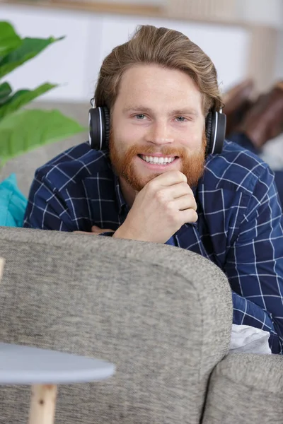 Χαρούμενος Νεαρός Άνδρας Χαλαρώνοντας Στον Καναπέ Ακουστικά — Φωτογραφία Αρχείου