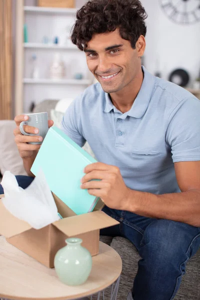 Handsome Young Man Opening Box Parcel Home — Stok fotoğraf