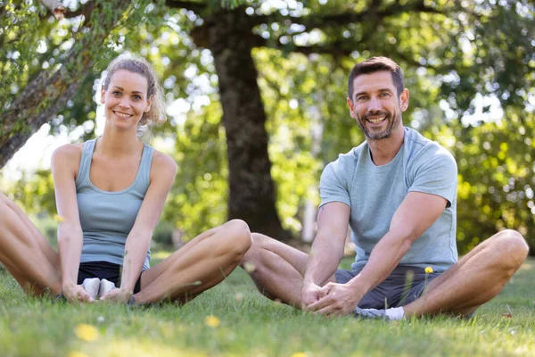 Healthy Couple Stretching Legs Grass Park — Zdjęcie stockowe