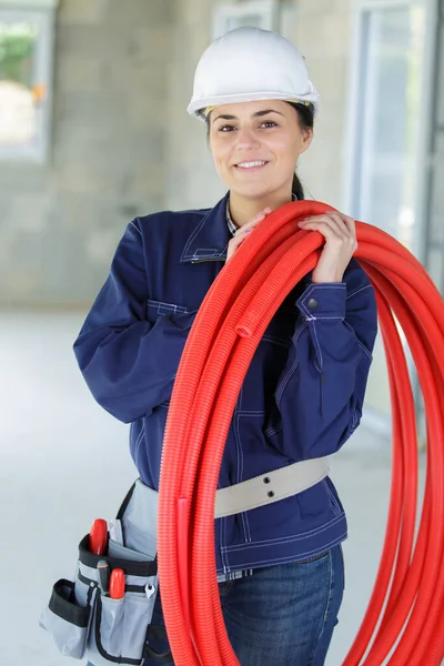 Female Worker Holding Reel Red Pipe Her Shoulder — Stock fotografie