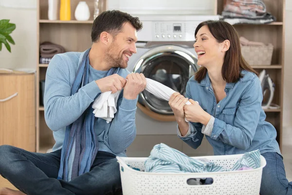 Smiling Couple Putting Clothes Washing Machine Together — Stockfoto