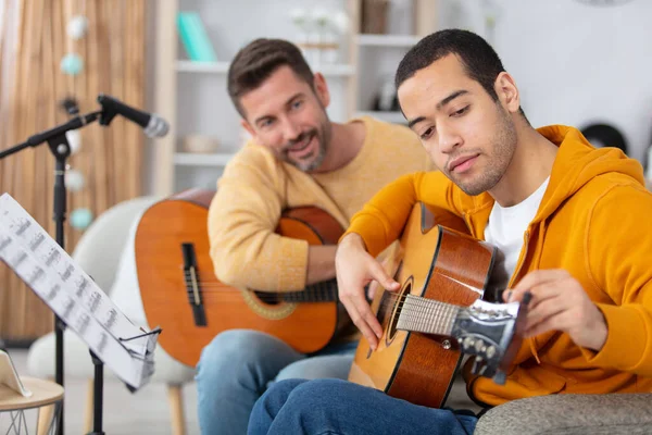 Adult Man Watches Teen Tunes His Guitar — ストック写真