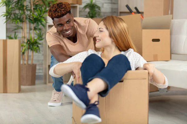 Happy Young Man Pushing Woman Sitting Cardboard Box — Fotografia de Stock