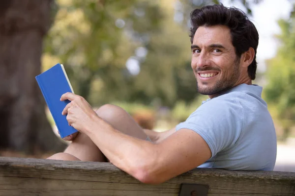 Bonito Homem Sentado Parque Banco Segurando Livro Aberto — Fotografia de Stock