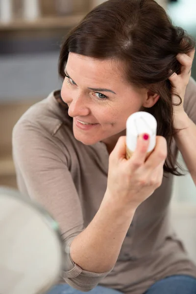 beautiful woman applying hair spray