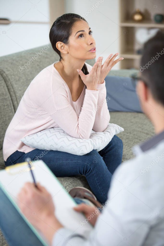 Female psychologyst therapy session with client indoors sitting taking notes