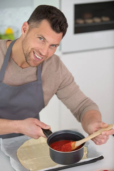 Ein Mann Der Eine Pizza Zubereitet Legt Tomatensauce Auf Teig — Stockfoto