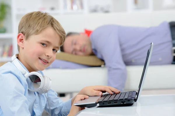 Bambino Sul Computer Portatile Che Sorriso Sfacciato Mentre Padre Dorme — Foto Stock