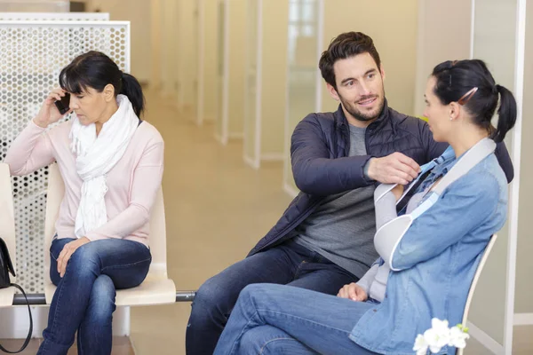 woman with broken arm in scarf waiting in hospital