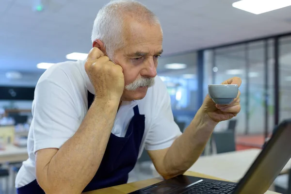 Gelangweilt Dreinblickender Älterer Barista Liest Aus Einem Laptop — Stockfoto