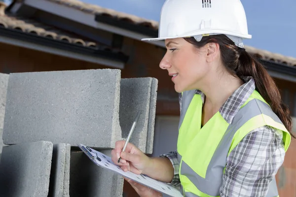 セメントブロックをチェックする女性建設労働者 — ストック写真