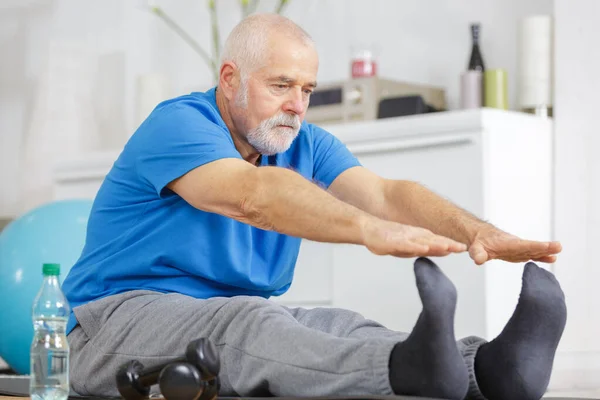 Senior Man Stretching Legs Indoors Stock Image