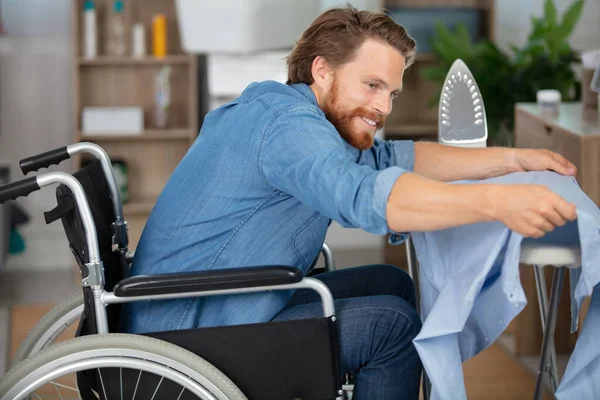 Νεαρός Αναπηρική Καρέκλα Κάνει Σιδέρωμα Στο Σπίτι — Φωτογραφία Αρχείου