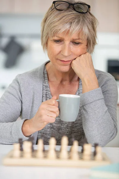 Ηλικιωμένη Γυναίκα Κρατώντας Κύπελλο Σκέφτεται Επόμενη Κίνηση Σκάκι — Φωτογραφία Αρχείου