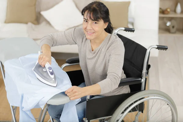 Mujer Feliz Madura Silla Ruedas Planchado Casa —  Fotos de Stock