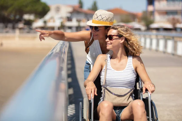 坐轮椅的快乐女人和海边的朋友 — 图库照片