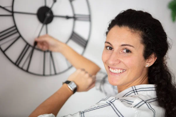 年轻女人在墙上的时钟上改变时间 — 图库照片