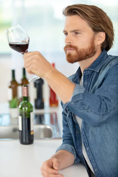 家で傾いたワイングラスを見る男の肖像画 — ストック写真