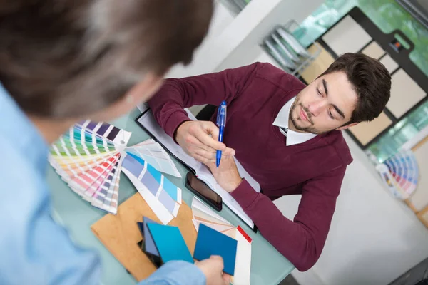 オフィスの顧客が色を選ぶ男性インテリアデザイナー — ストック写真