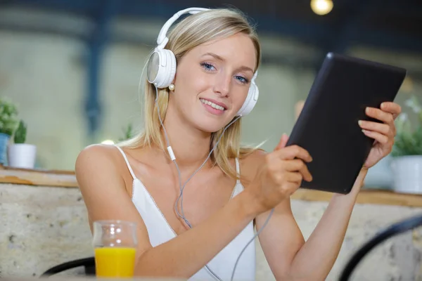 young woman using tablet and headphone in the bistro